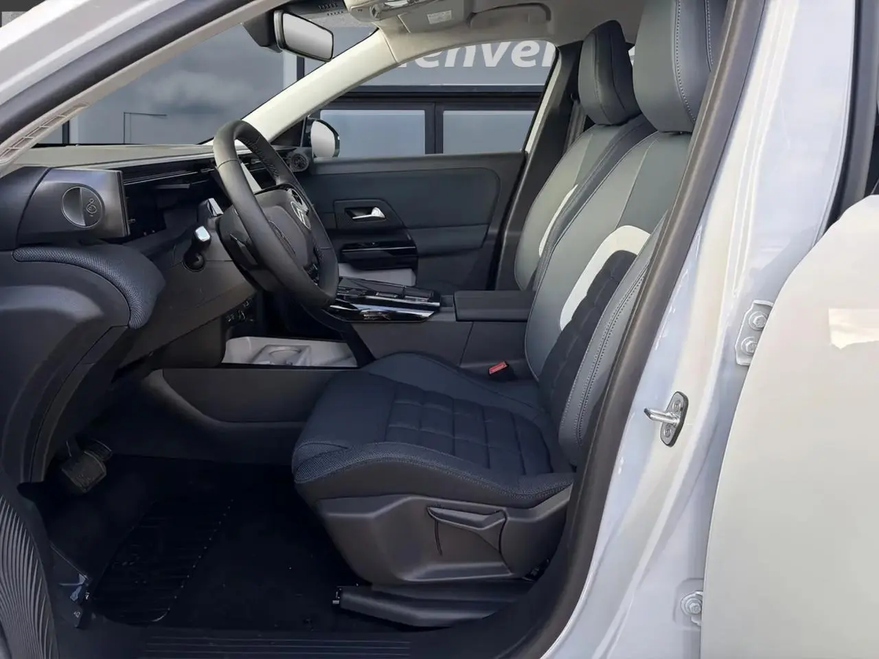 Vue intérieure côté conducteur du Citroën C5 Aircross blanc, mettant en valeur les sièges tissu bleu et le volant multifonction.