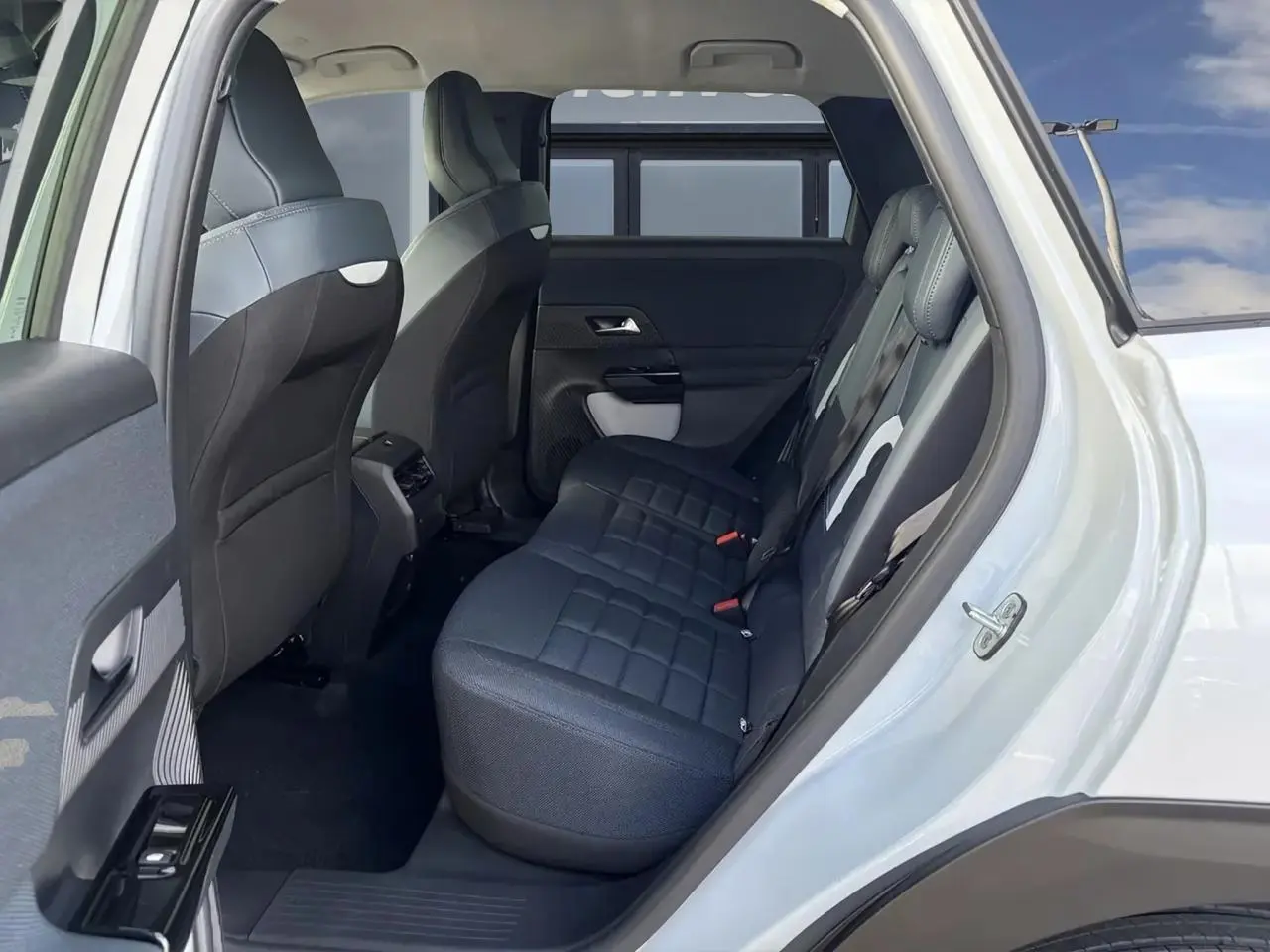 Vue intérieure côté droit des sièges arrière en tissu bleu du Citroën C5 Aircross blanc avec portière ouverte.