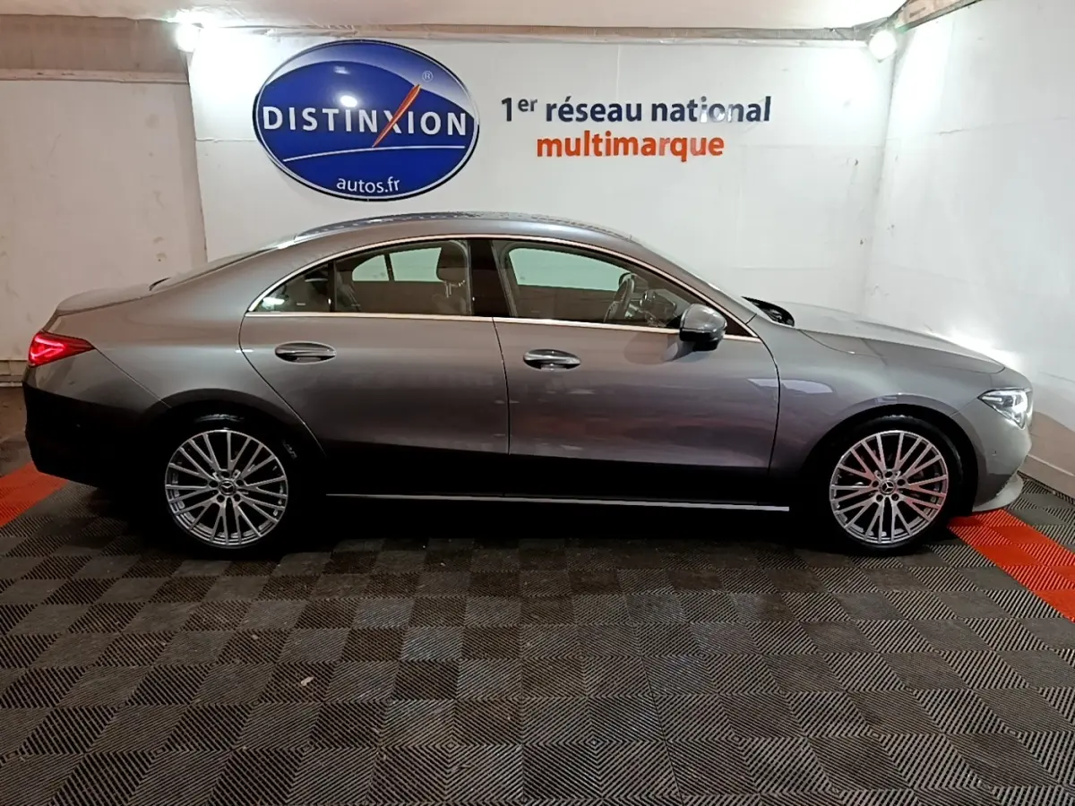 Vue de profil côté gauche d'une Mercedes CLA 180 d Business Line gris clair dans un showroom intérieur.