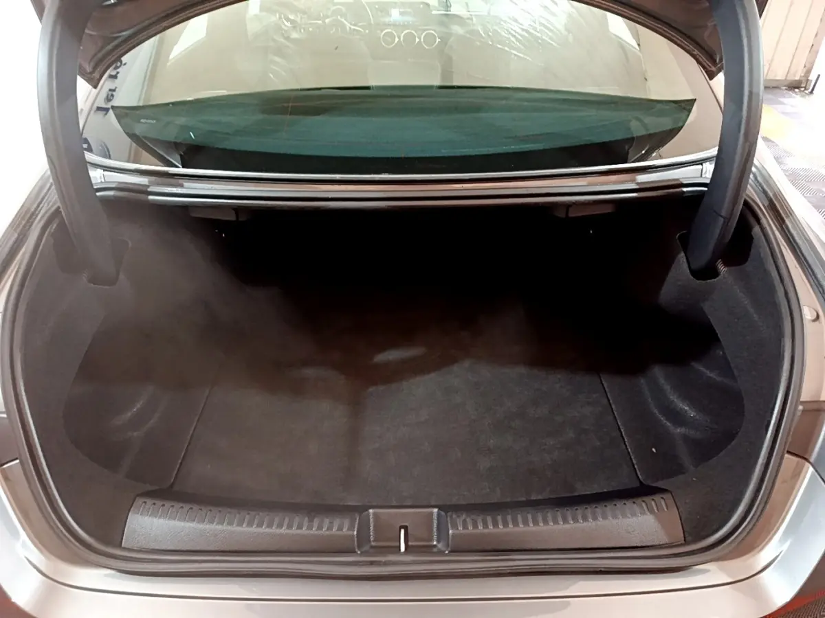 Coffre ouvert d'une Mercedes CLA 180 d gris clair, vue arrière montrant l'espace de rangement vide.