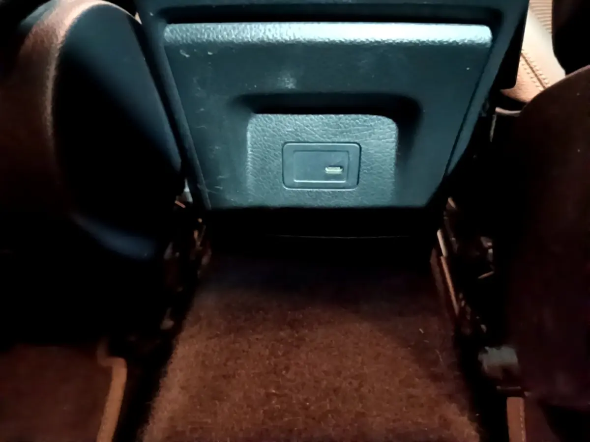 Vue rapprochée de la prise USB arrière entre les sièges noirs de la Mercedes CLA 180 d Business Line gris clair.