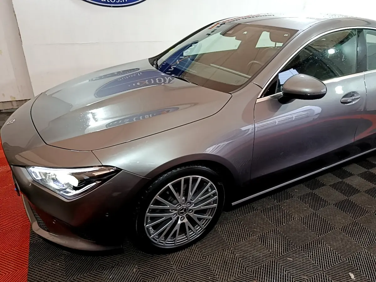 Mercedes Classe CLA 180 d gris clair vue 3/4 avant droit avec jantes alliage et phares LED allumés.