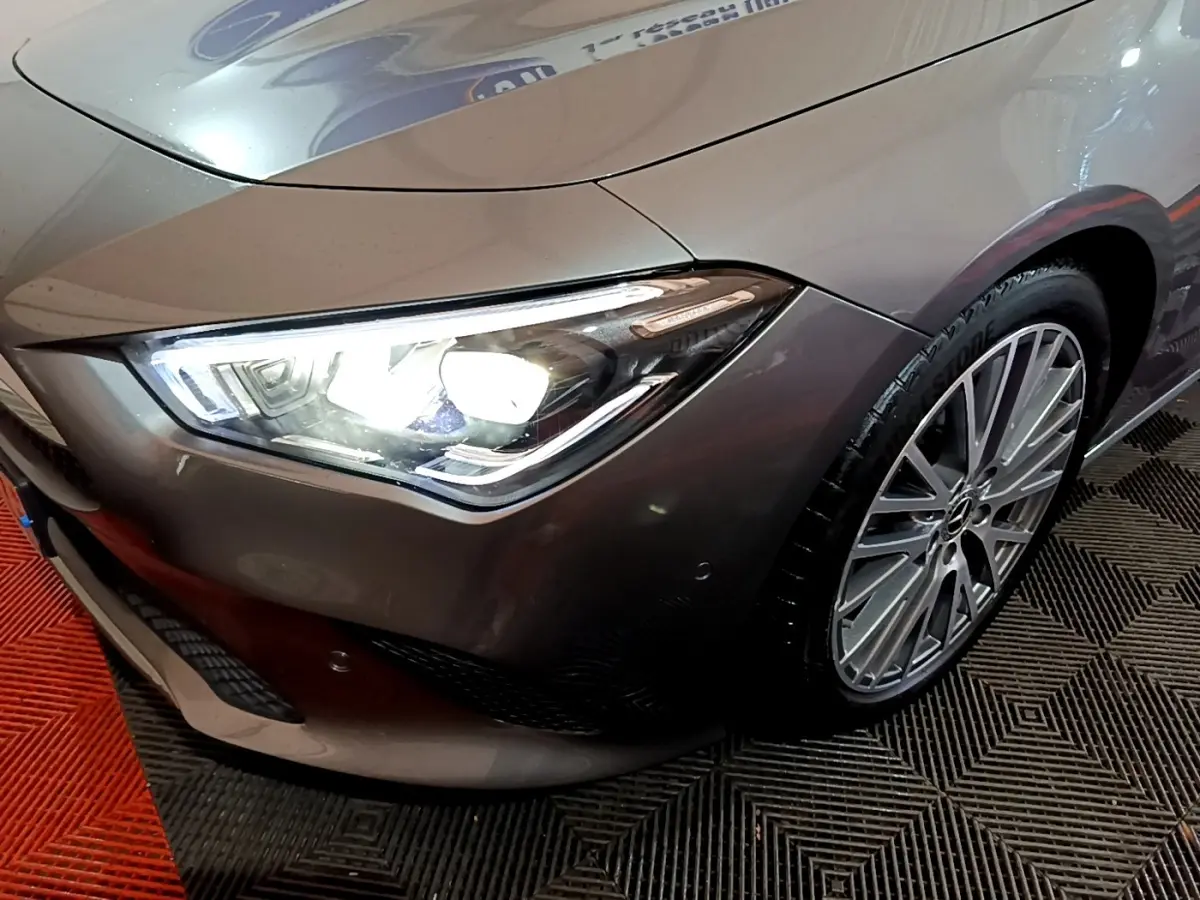 Gros plan sur l'avant droit gris clair d'une Mercedes CLA 180 d Business Line avec phare LED allumé et jante alliage.