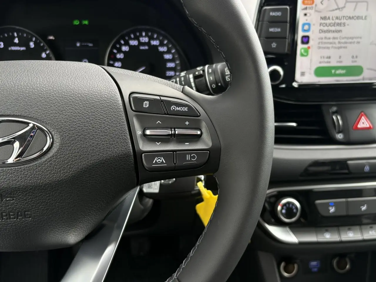 Gros plan sur le volant cuir gris et tableau de bord d’une Hyundai i30 SW 2025 avec écran tactile Apple Car Play visible.