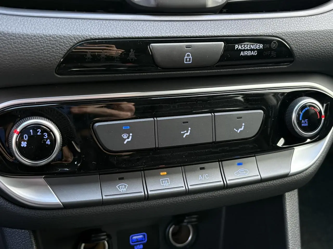 Détail de la console centrale de la Hyundai i30 SW T-GDI 120 Modern 2025, avec commandes de climatisation manuelle et boutons rétroéclairés.