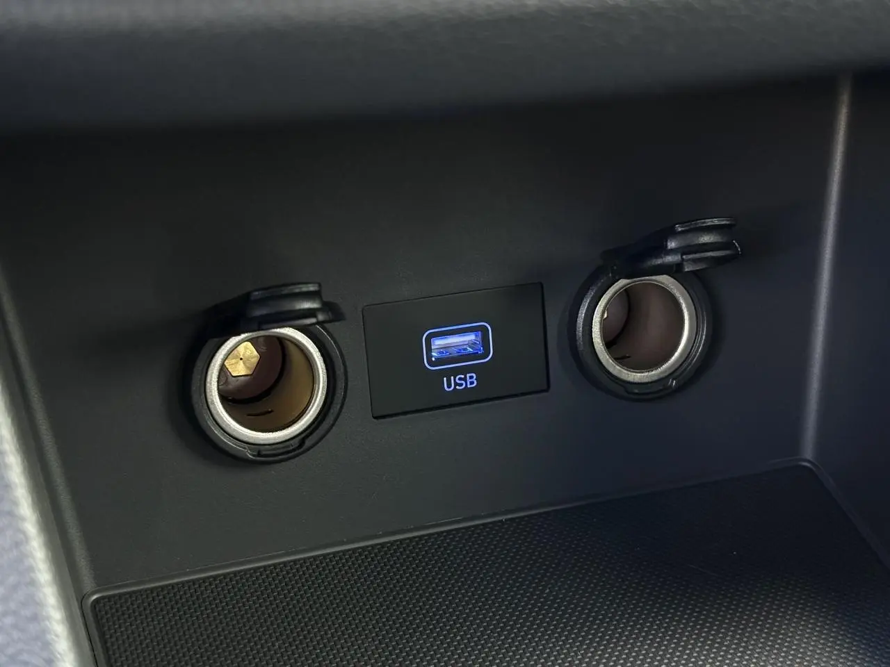 Gros plan sur la prise USB et les deux allume-cigares dans l'habitacle noir de la Hyundai i30 SW T-GDI 120 Modern.