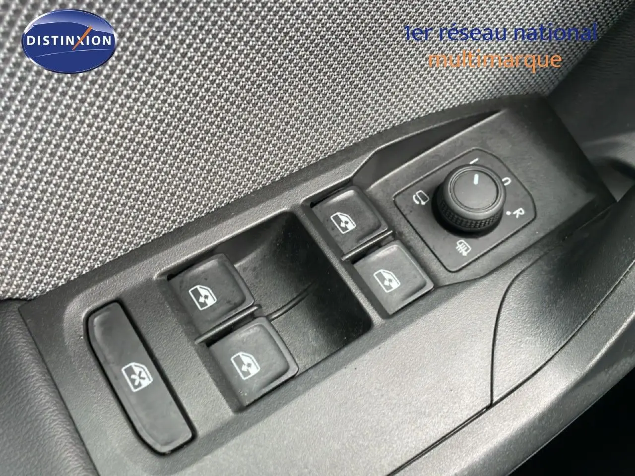 Gros plan sur les commandes des vitres électriques et rétroviseurs côté conducteur d’un SEAT Leon gris métallique.