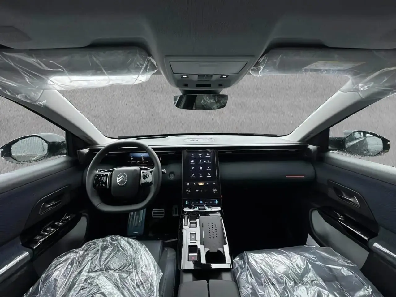 Vue intérieure avant du Citroën C5 Aircross hybride 2026 avec tableau de bord noir et écran tactile vertical central.