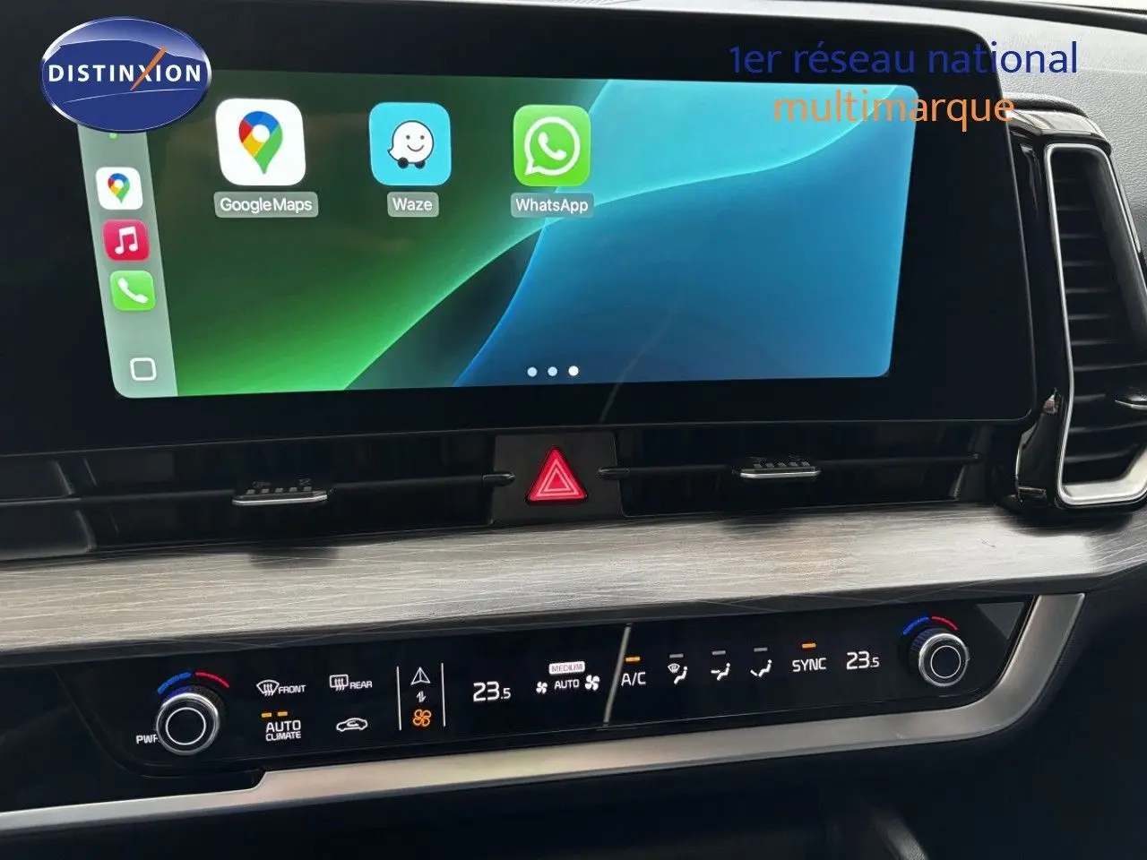 Vue rapprochée de la console centrale du Kia Sportage blanc nacré, avec écran tactile et commandes climatisation.