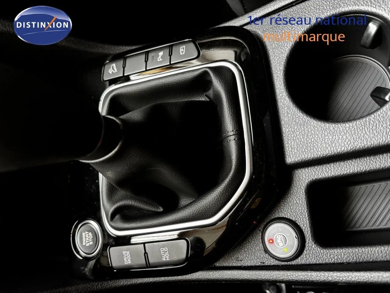 Gros plan sur la console centrale noire du Kia Sportage blanc nacré, montrant le levier de vitesse manuel et les boutons de contrôle.