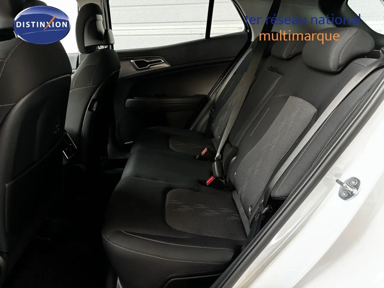 Vue intérieure côté droit des sièges arrière noirs en tissu du Kia Sportage blanc nacré 2025, porte ouverte.