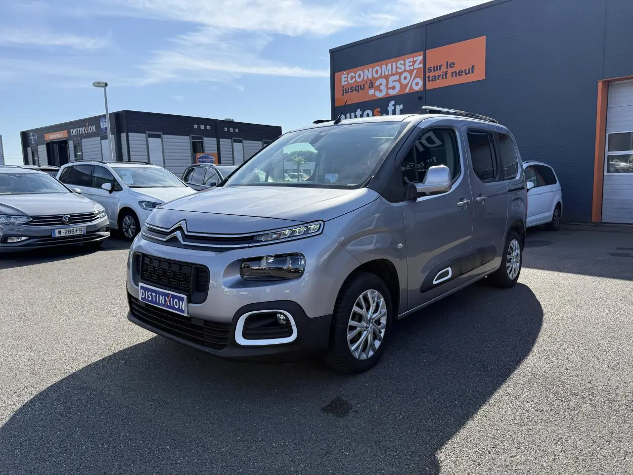 Citroën Berlingo gris foncé vu en 3/4 avant droit, avec ses phares distinctifs et coques de rétroviseurs ton caisse.