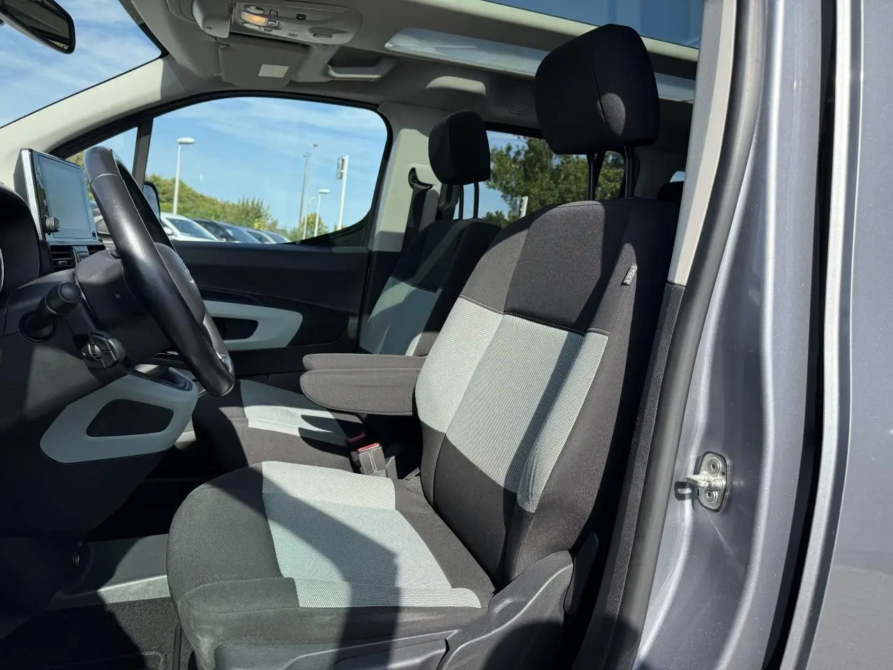 Vue intérieure côté conducteur du Citroën Berlingo gris foncé 2018, sièges bi-ton et tableau de bord moderne.