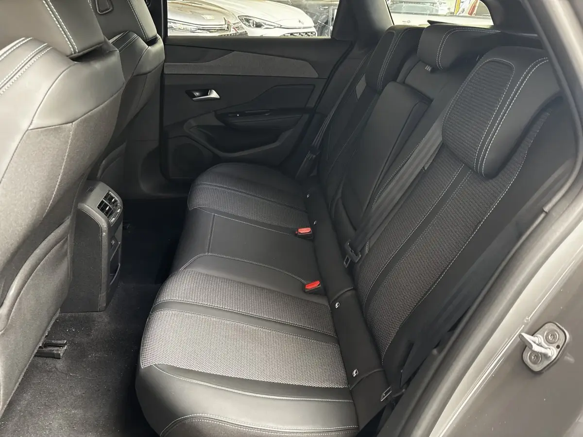 Vue intérieure arrière droite des sièges noirs en tissu et cuir de la Peugeot 308 PureTech 130 Allure 2024.