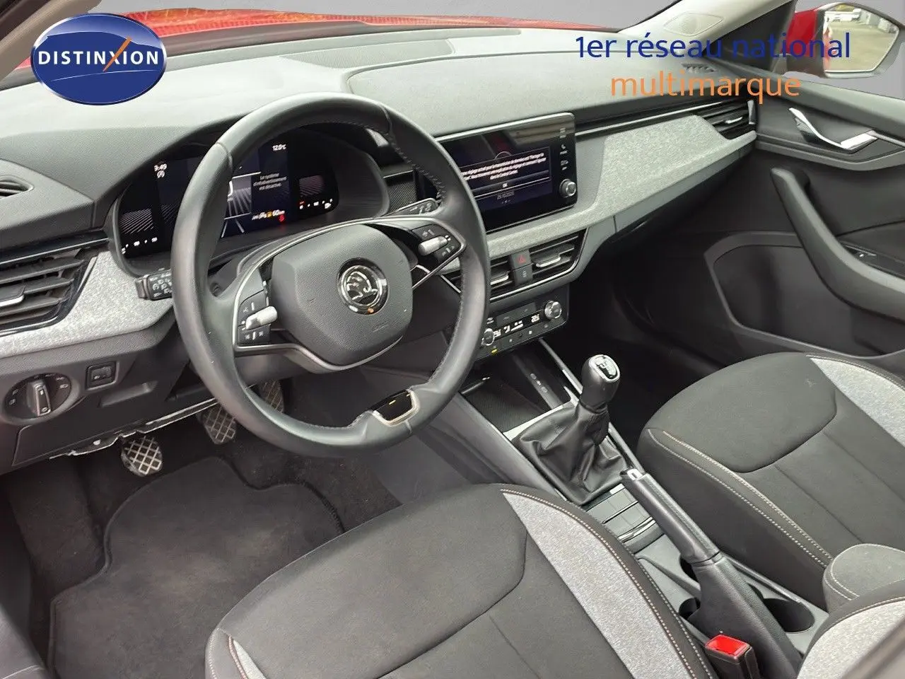 Intérieur du Skoda Kamiq 2024, vue côté conducteur sur tableau de bord, volant, levier de vitesses manuel et sièges gris/noir.