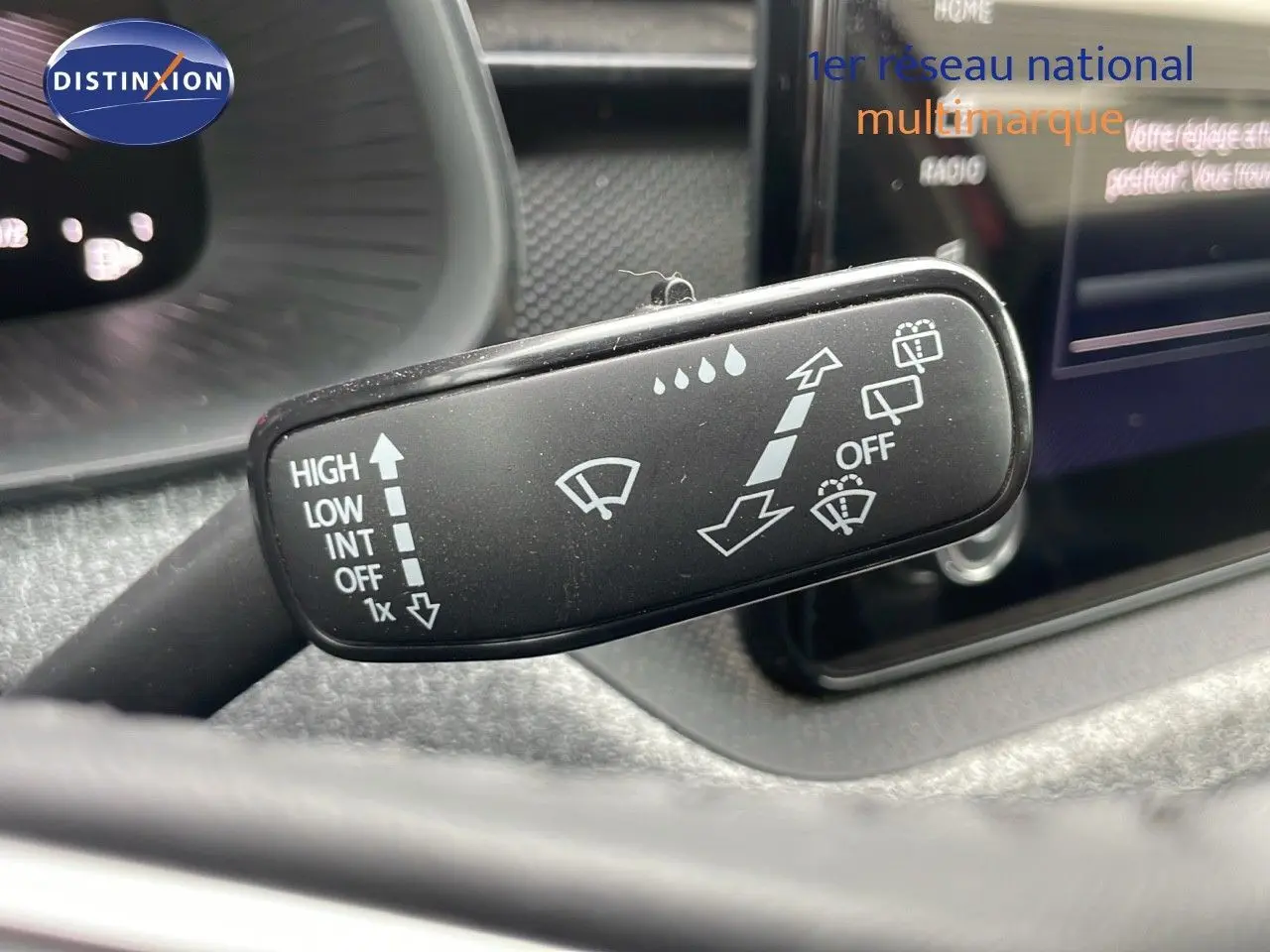 Gros plan sur la commande des essuie-glaces du Skoda Kamiq 2024, avec tableau de bord et écran tactile en arrière-plan.