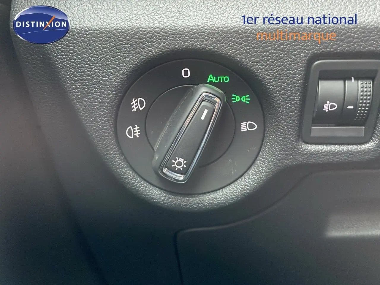 Gros plan sur le bouton de commande des phares dans l'habitacle d'une Skoda Kamiq rouge Velvet Metal 2024.