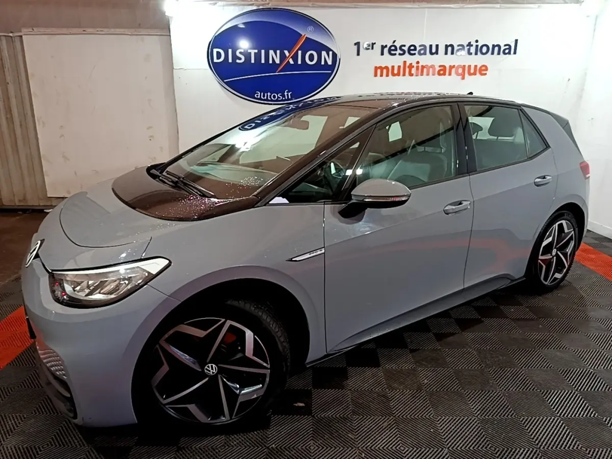 Vue 3/4 avant droit d'une Volkswagen ID.3 77 kWh Pro S gris foncé en intérieur, avec jantes distinctives et logo visible.
