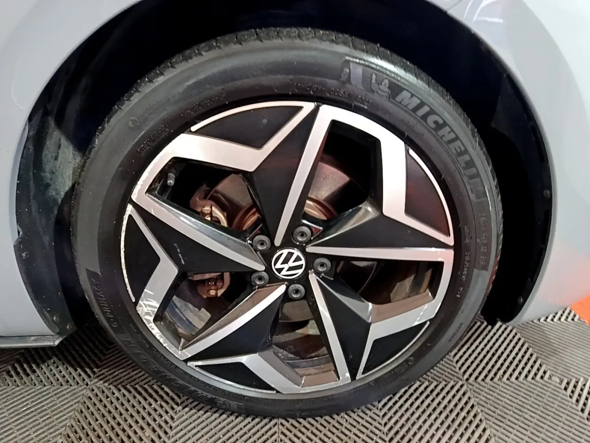 Gros plan sur la roue avant gauche d’un Volkswagen ID.3 gris foncé avec jante alliage noire et argentée.