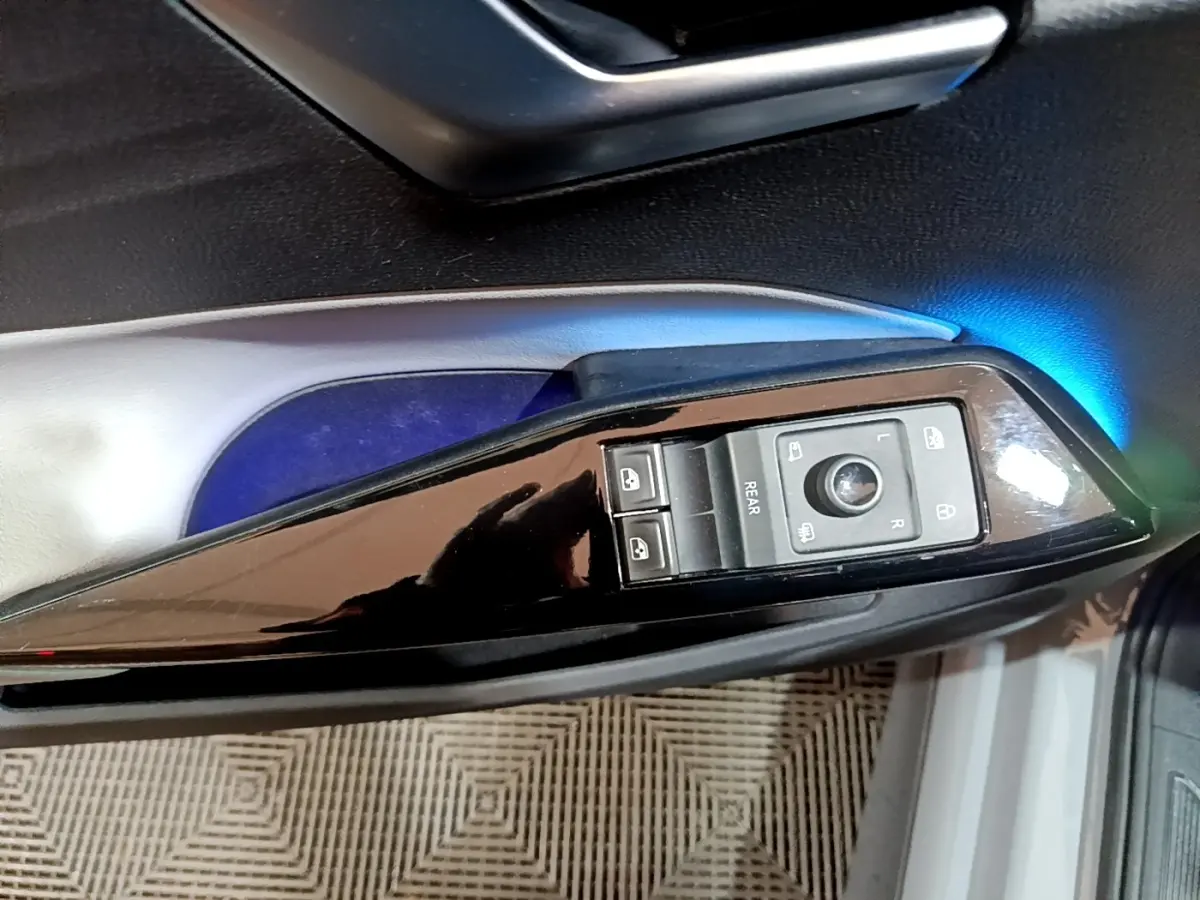 Gros plan sur la commande des rétroviseurs et vitres côté conducteur du Volkswagen ID.3 gris foncé avec éclairage d’ambiance bleu.