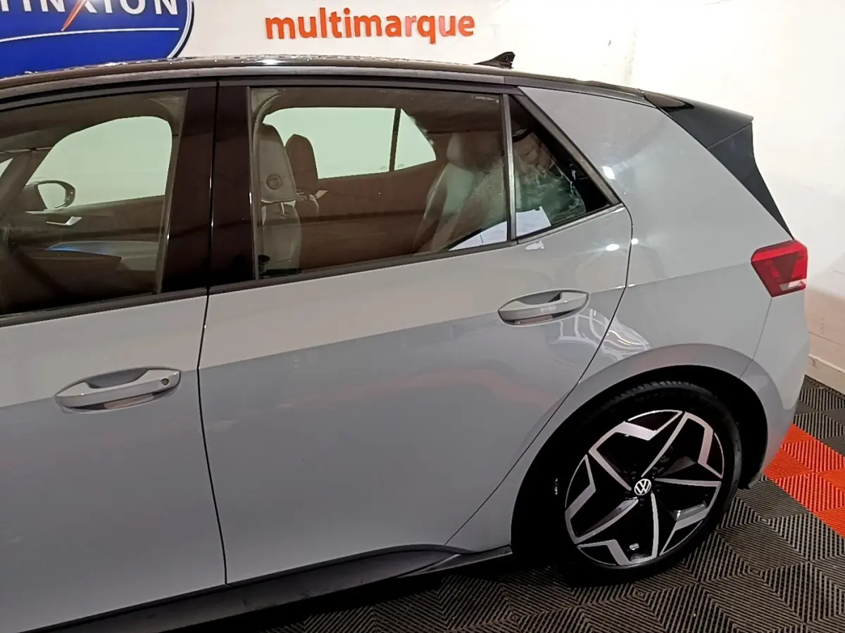 Vue latérale droite du Volkswagen ID.3 gris foncé avec jantes noires et design moderne, en intérieur showroom.