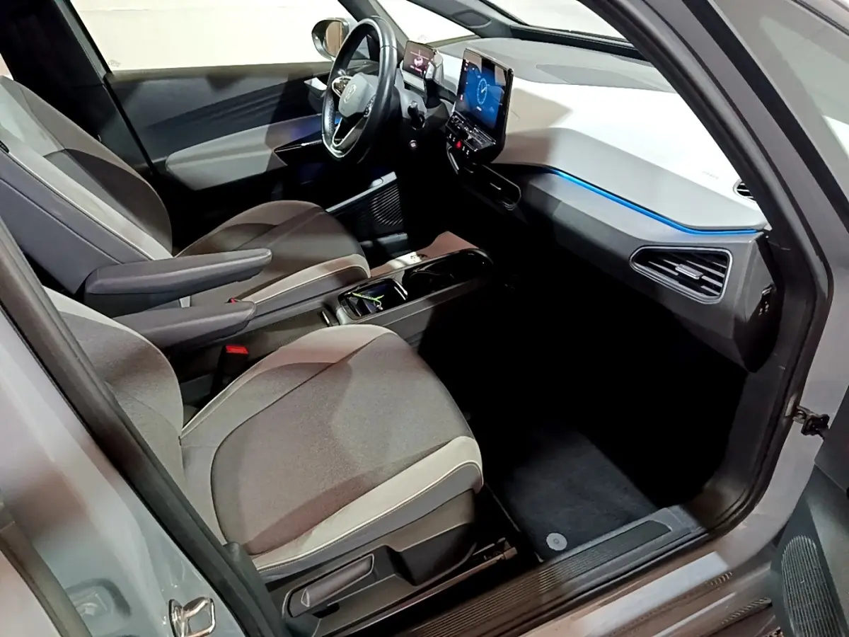 Vue intérieure côté conducteur du Volkswagen ID.3 77 kWh Pro S 2022, avec tableau de bord blanc et éclairage bleu.