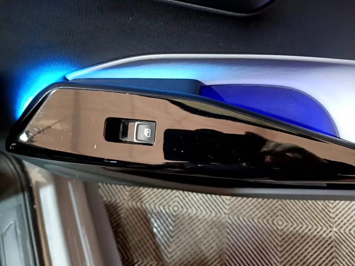 Gros plan sur l'interrupteur de lève-vitre côté conducteur du Volkswagen ID.3 77 kWh Pro S gris foncé, éclairage bleu intérieur.