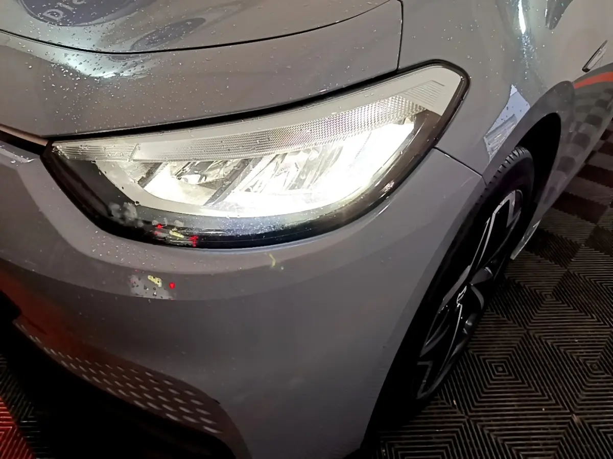 Gros plan sur le phare avant droit allumé d'une Volkswagen ID.3 77 kWh Pro S gris foncé avec jante noire.
