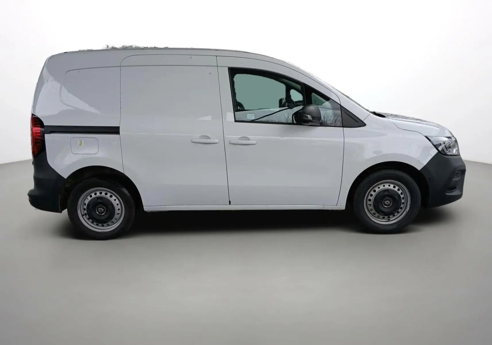 Profil droit d’un Renault Kangoo Van blanc 2024 avec portes latérales coulissantes et jantes acier simples.