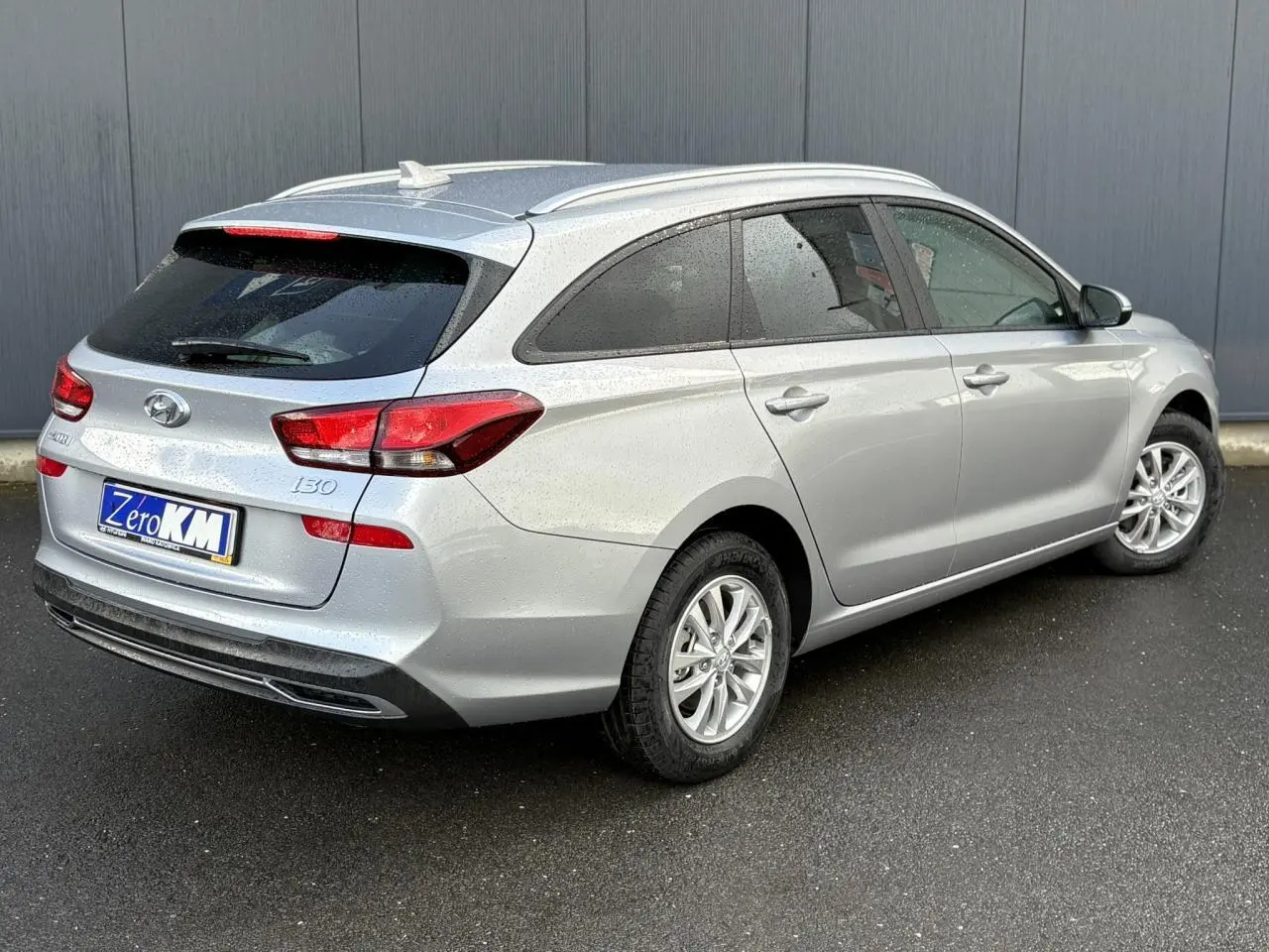 Vue 3/4 arrière droite d'une Hyundai i30 SW T-GDI 120 gris argent métallisé avec vitres arrière surteintées et jantes alliage.