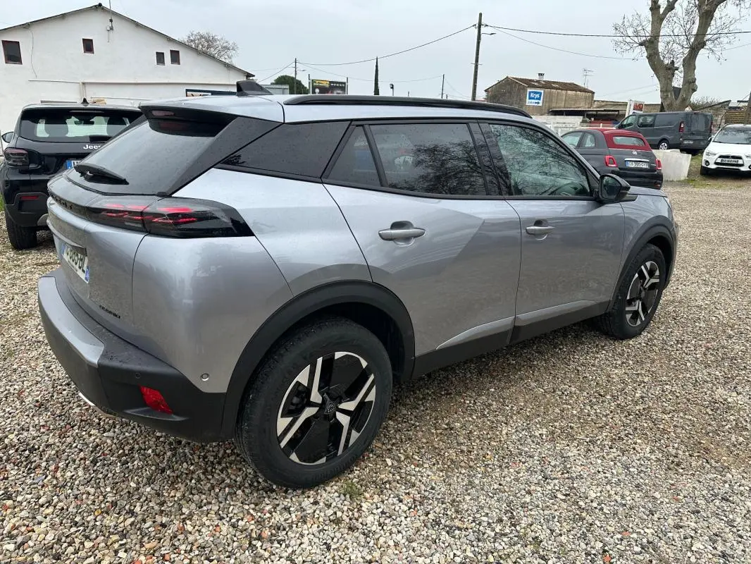 Peugeot 2008 Hybrid gris en 3/4 arrière droit, avec barres de toit et jantes alliage 17 pouces visibles.