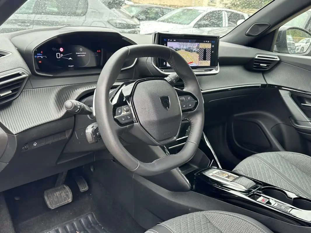 Vue intérieure côté conducteur du Peugeot 2008 Hybrid 136 gris, avec tableau de bord numérique et écran tactile central.