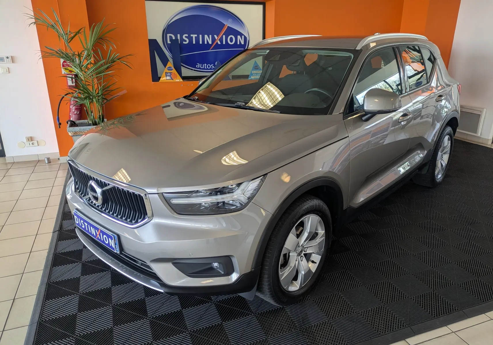Vue 3/4 avant droite d'un Volvo XC40 marron clair en showroom avec jantes alliage et toit panoramique.