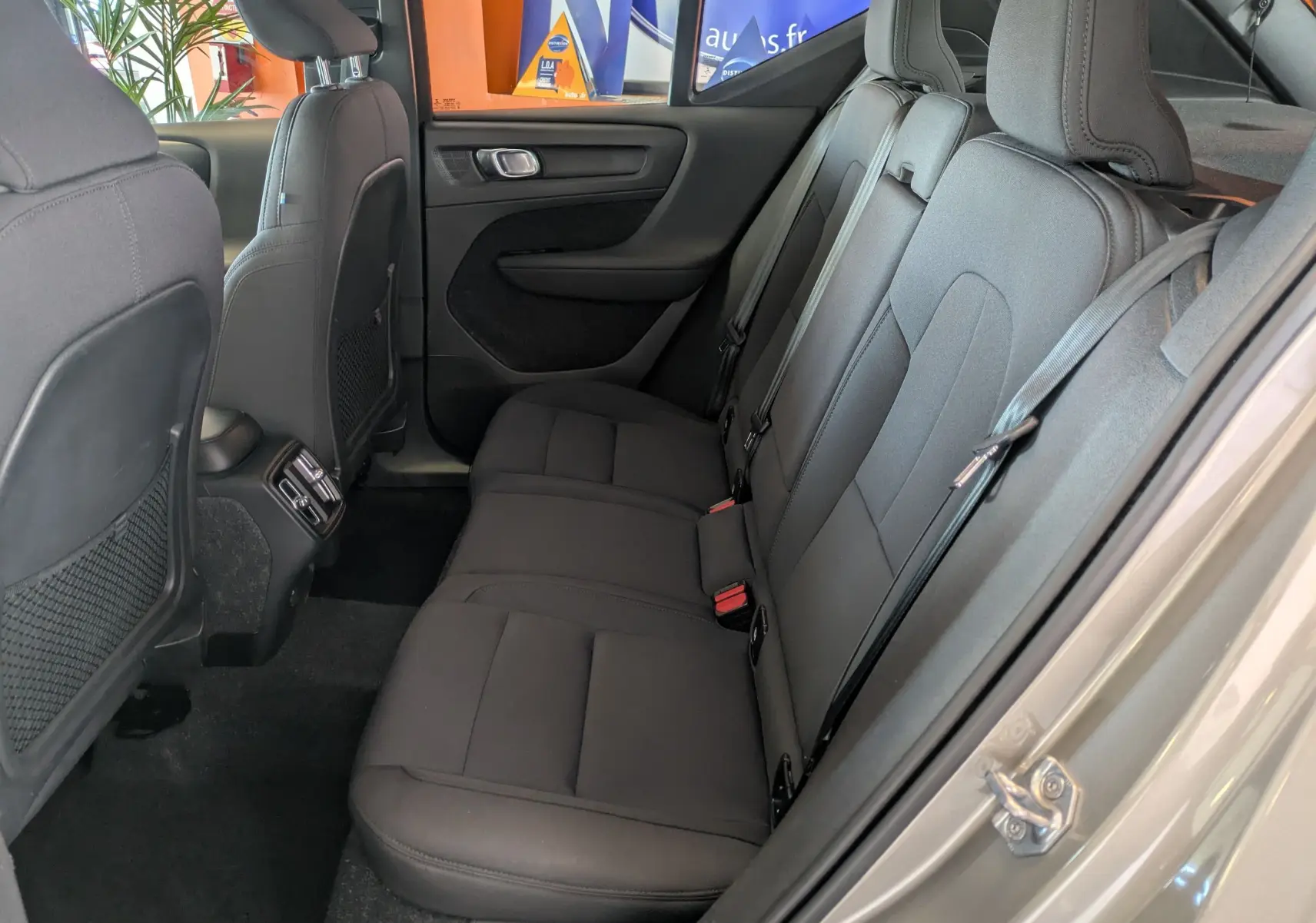 Vue intérieure côté droit des sièges arrière noirs du Volvo XC40 Momentum 2021, avec ceinture de sécurité et porte ouverte.