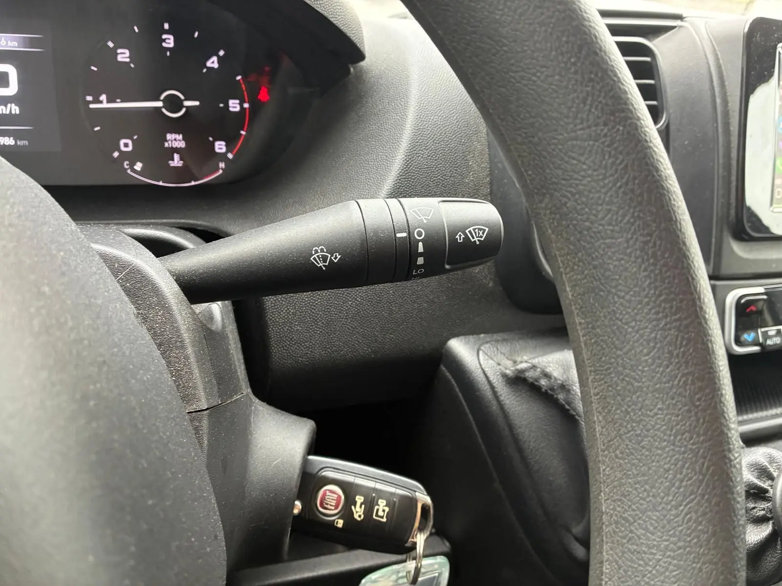 Vue rapprochée de l’intérieur du Fiat Ducato 2023, montrant le volant noir, le compteur et la clé insérée côté gauche.