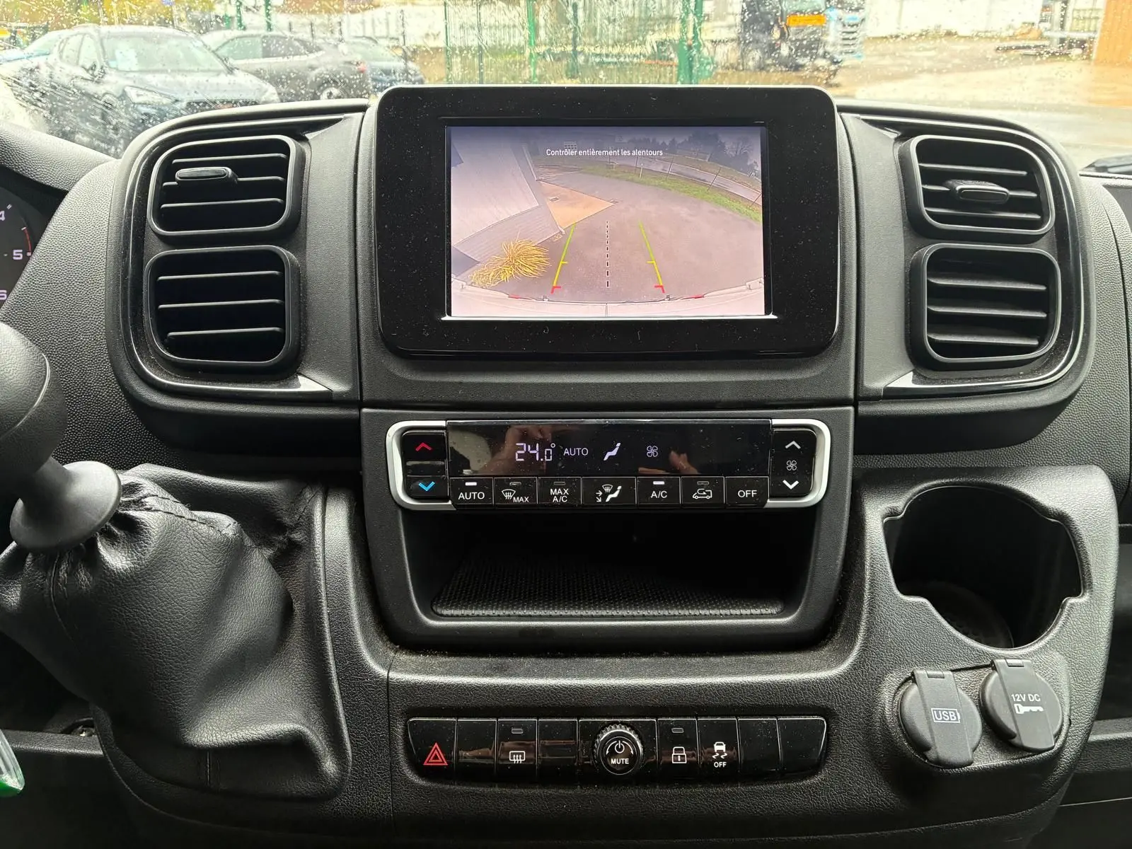 Vue rapprochée du tableau de bord noir du Fiat Ducato 2023 avec écran de caméra de recul et commande de climatisation.