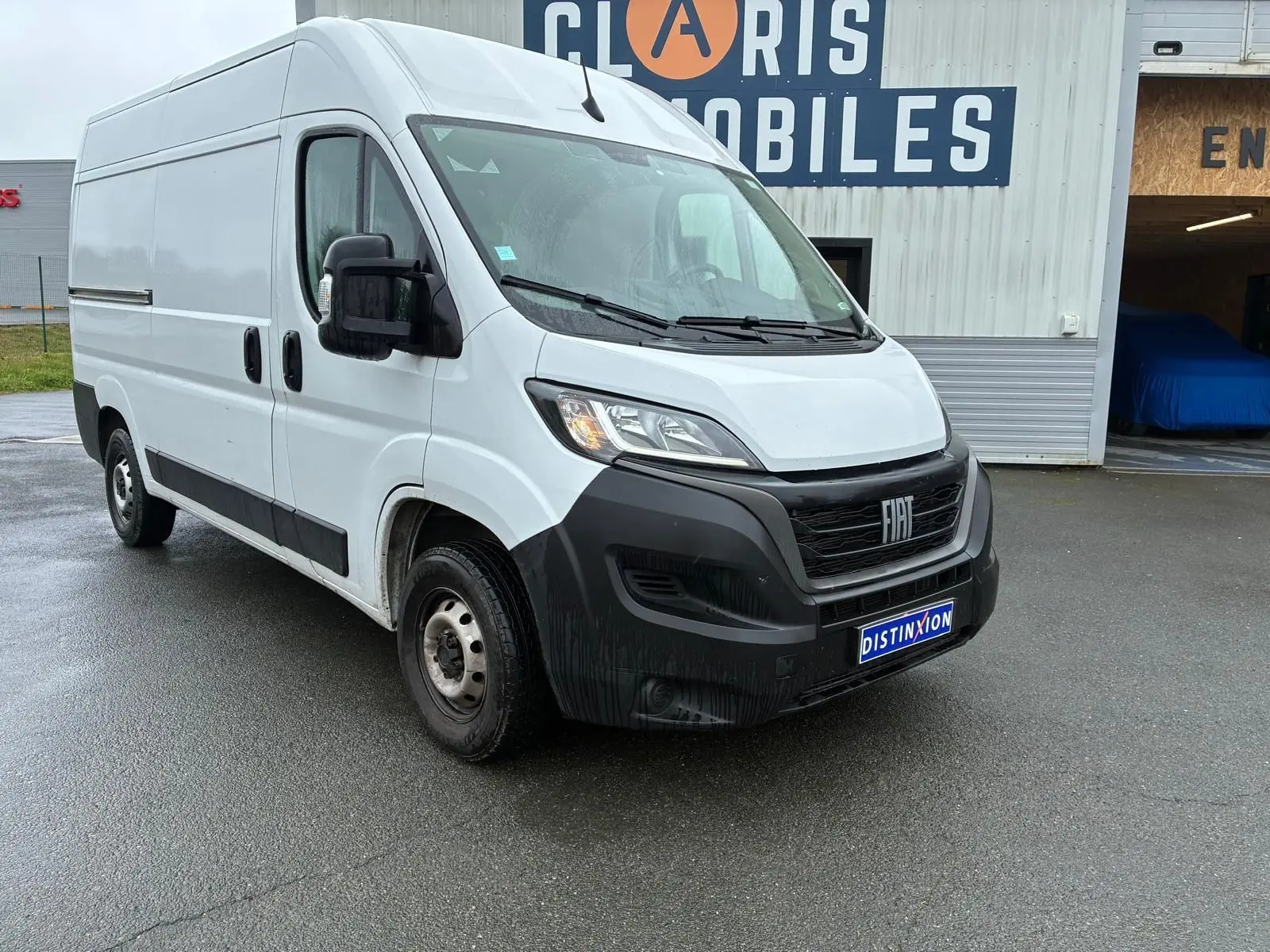 Fiat Ducato Fourgon blanc en 3/4 avant droit, avec pare-chocs noir et plaque Distinxion visible.
