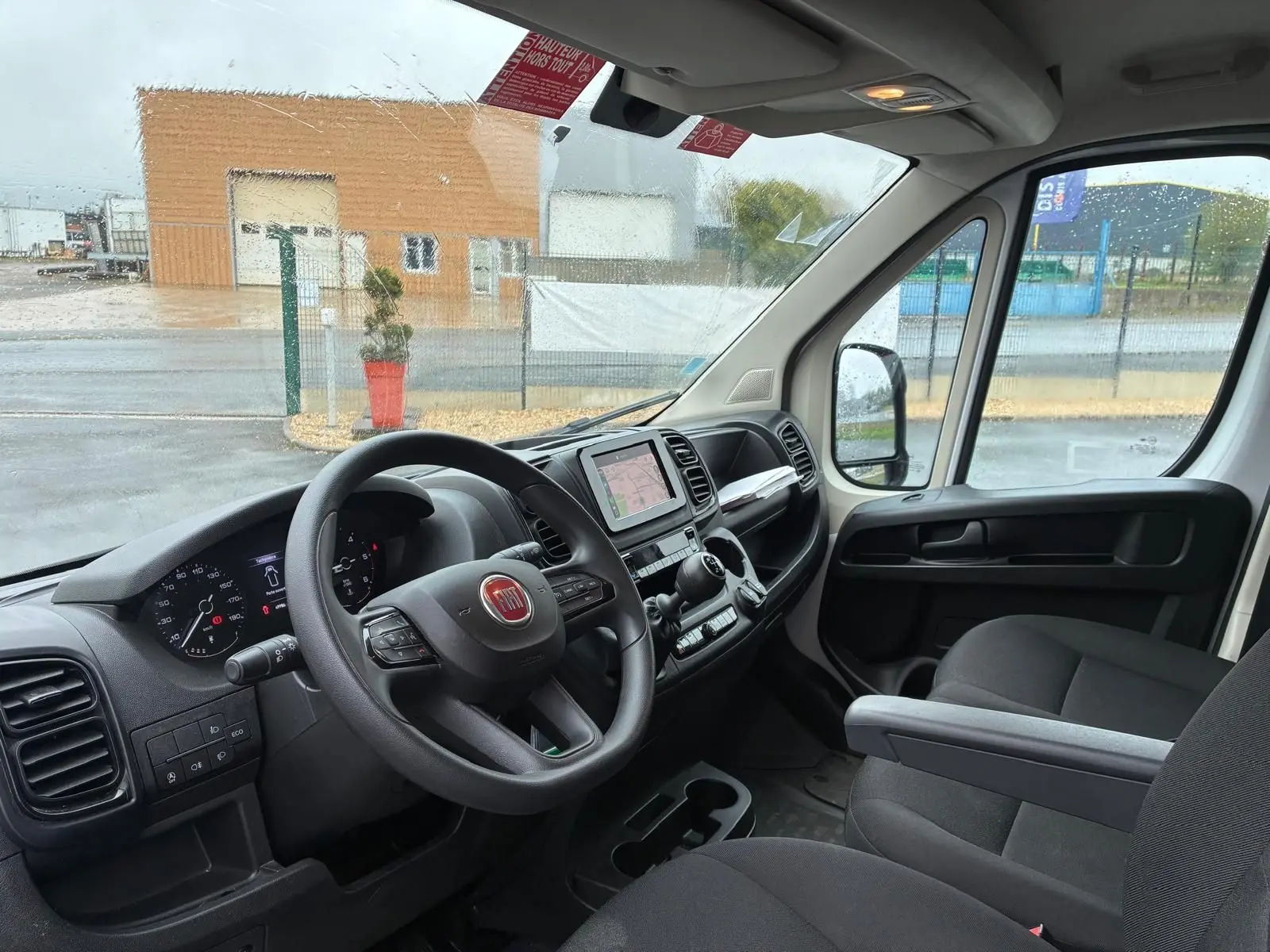 Vue intérieure côté conducteur du Fiat Ducato Fourgon blanc 2023, tableau de bord avec écran tactile et volant multifonction.