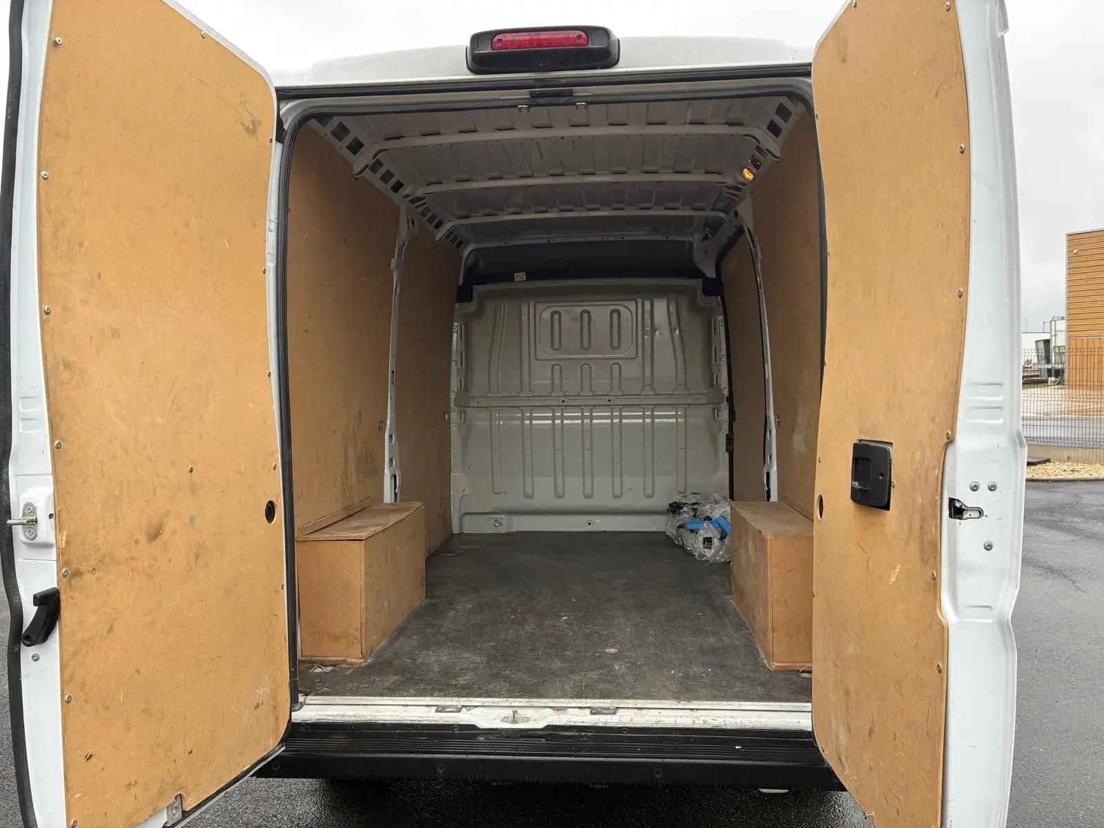 Vue arrière ouverte du fourgon blanc FIAT Ducato 2023, montrant l'intérieur vide avec parois en bois.