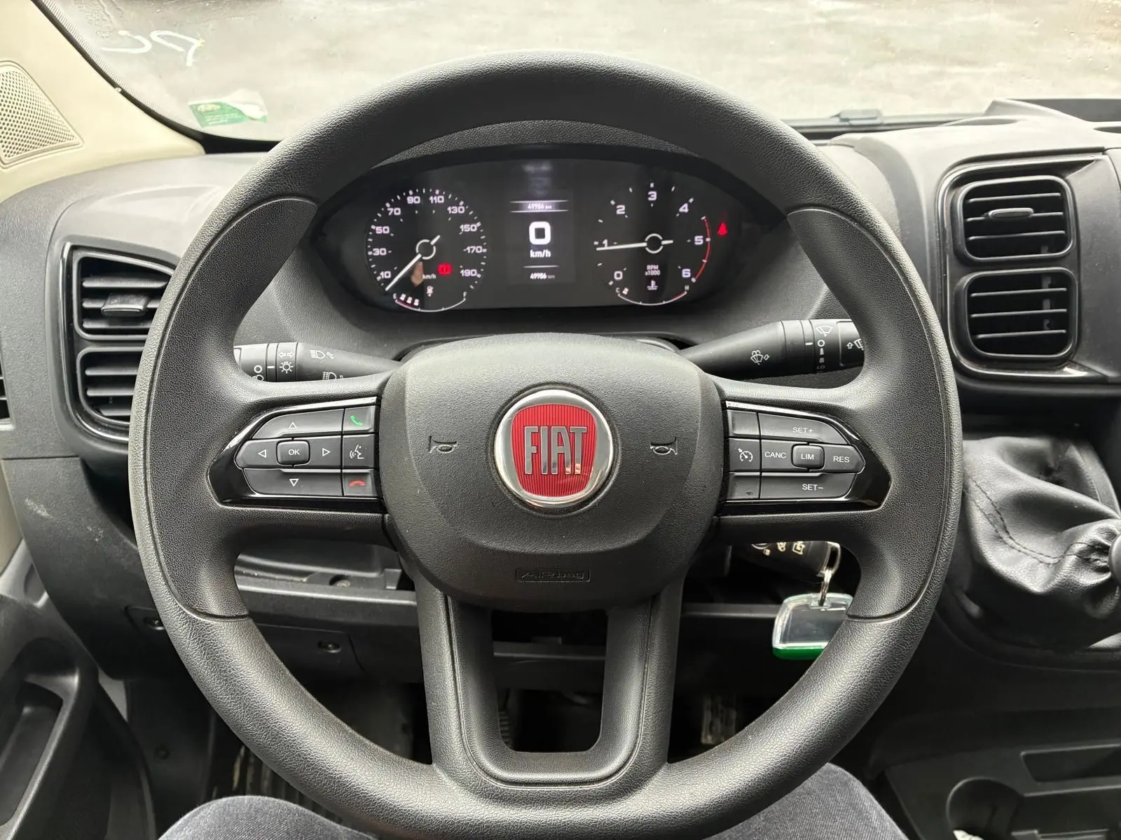 Vue intérieure centrée sur le volant noir du Fiat Ducato Fourgon 2023 avec tableau de bord et levier de vitesses visible à droite.