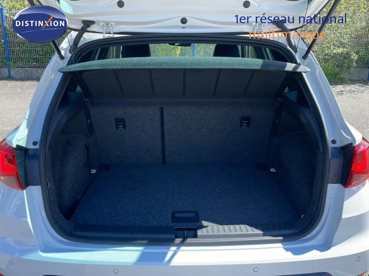 Vue arrière du coffre ouvert d'un SEAT Arona blanc à toit noir, montrant l'espace de chargement vide et la moquette grise.
