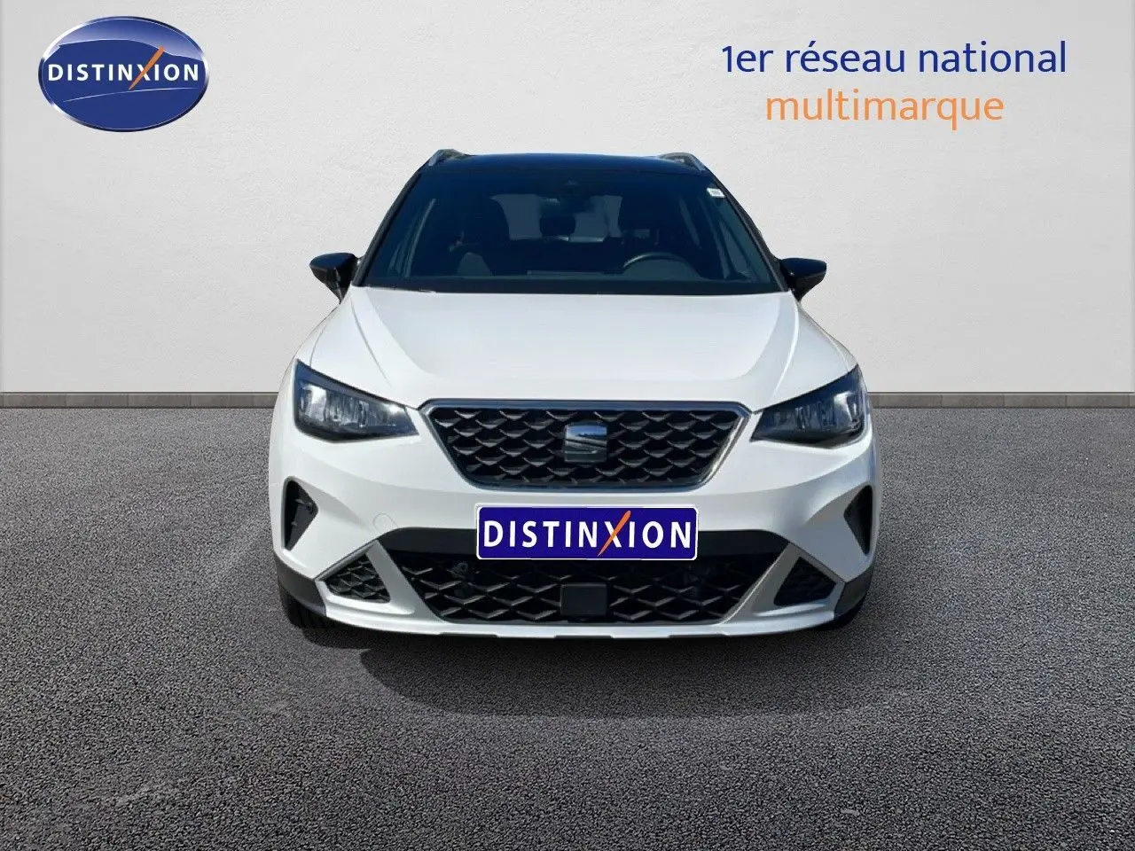 Vue frontale d'un SEAT Arona blanc avec toit noir, calandre noire et phares LED allumés.