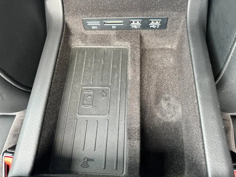 Gros plan sur la console centrale noire de l'Audi A6 Avant 2019, montrant le chargeur sans fil et ports USB intégrés.