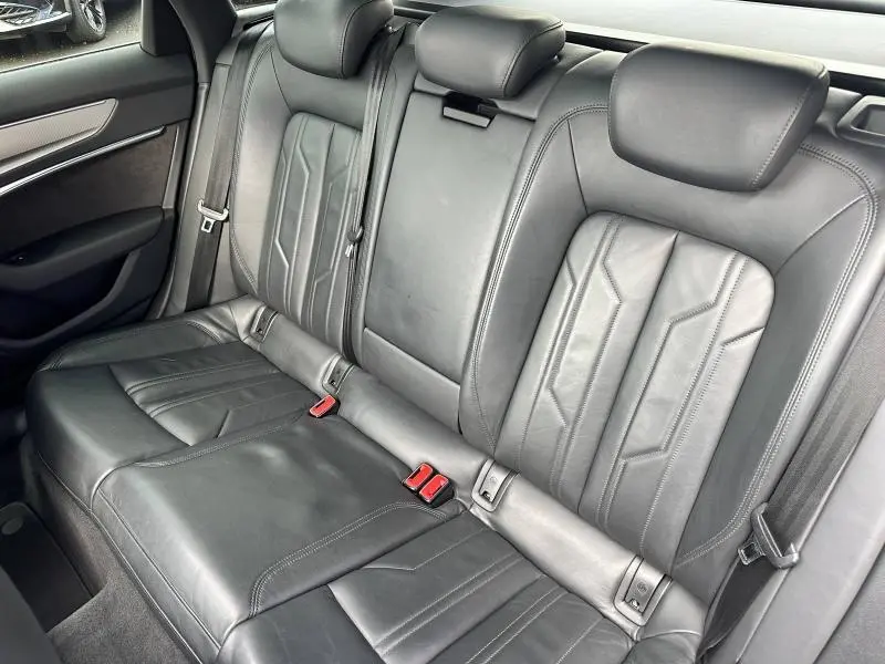 Vue latérale des sièges arrière en cuir noir de l'Audi A6 Avant 45 TDI S line, avec ceintures et appuie-têtes intégrés.
