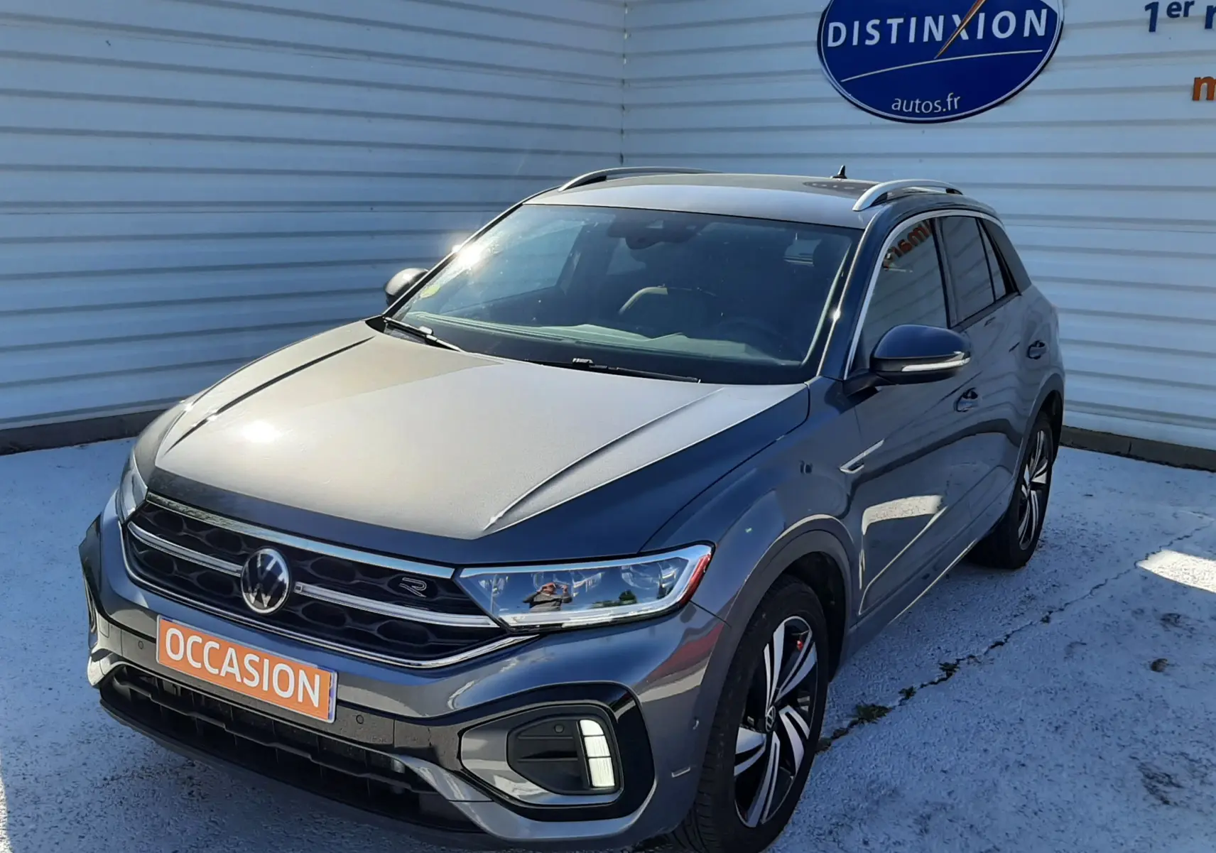 Volkswagen T-Roc gris Indium vue 3/4 avant droit, avec jantes alliage et badge R-Line visible.