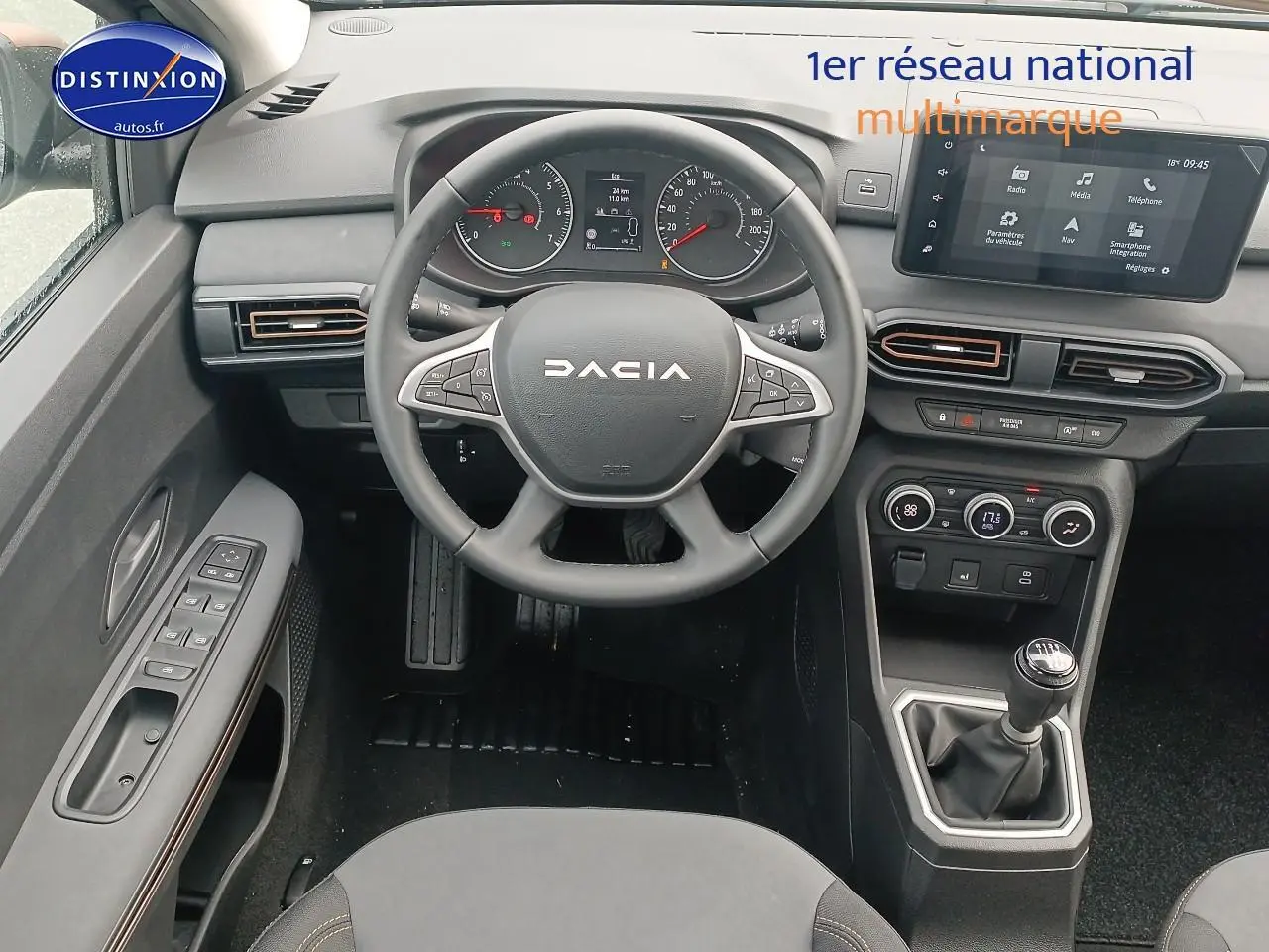 Vue intérieure du poste de conduite de la Dacia Sandero 2025 avec volant multifonction, écran tactile et levier de vitesse manuel.