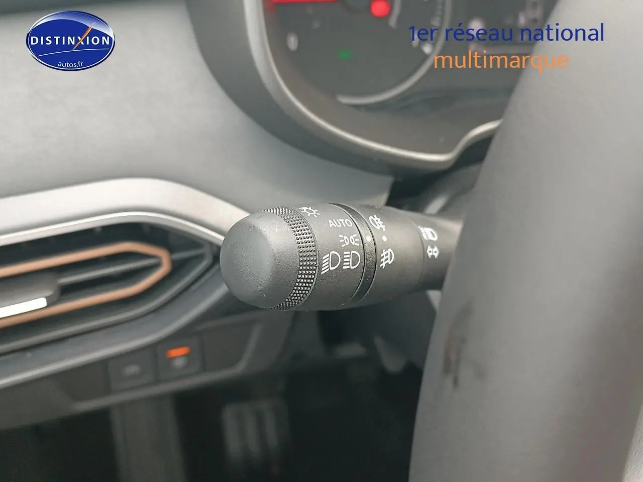 Gros plan sur la commande des phares à gauche du volant dans l'habitacle de la Dacia Sandero noire 2025