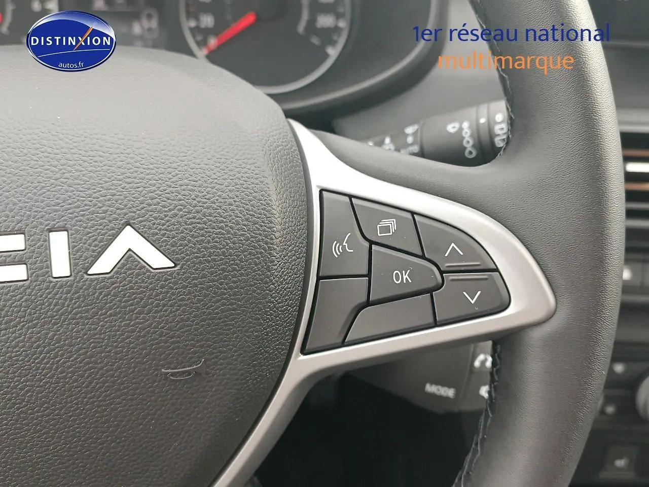 Gros plan sur les commandes au volant à droite du Dacia Sandero noir, montrant les boutons multifonctions et le logo partiel.