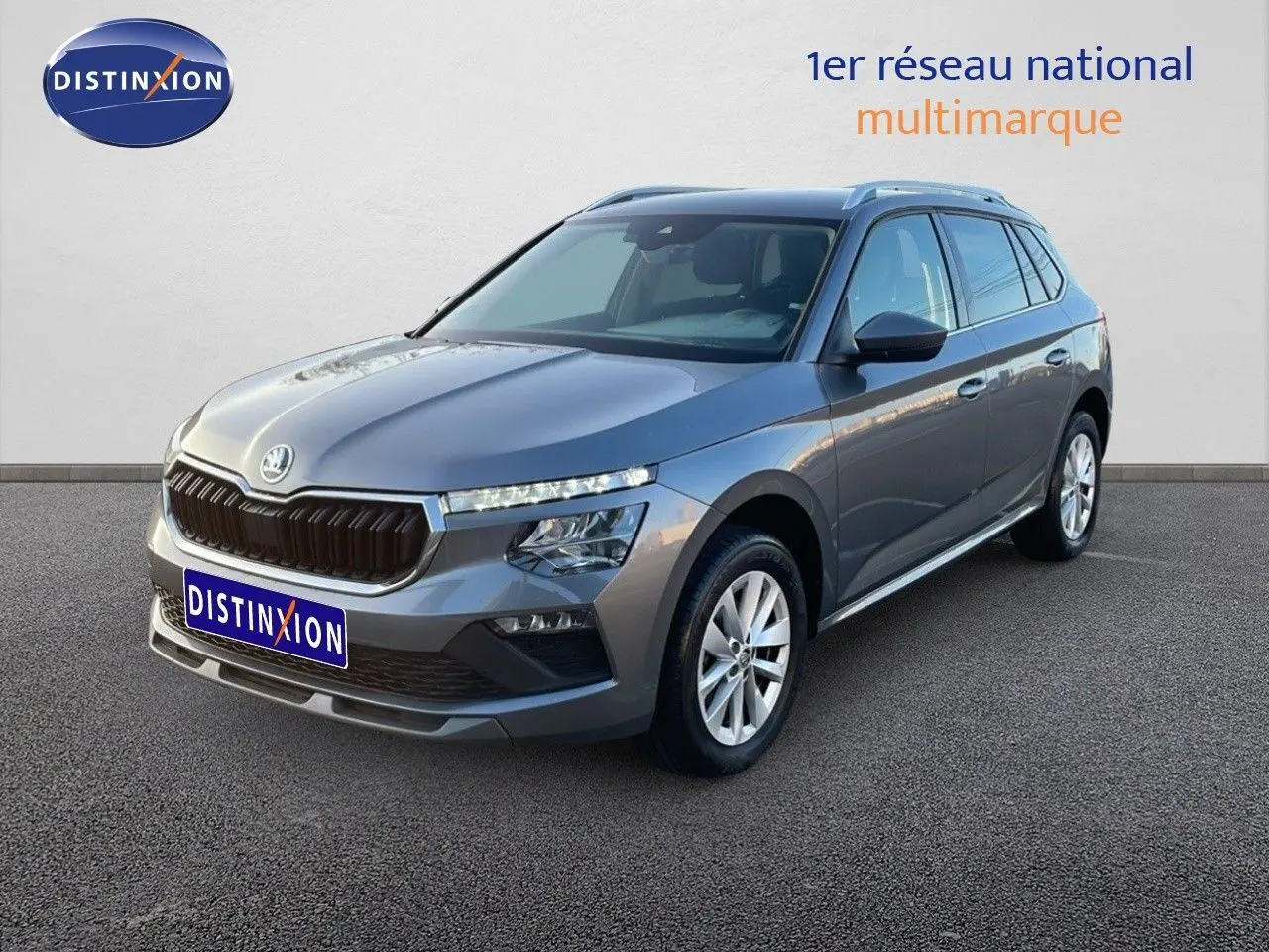 Vue 3/4 avant droite d'un Skoda Kamiq gris graphite métal 2024 avec calandre noire et jantes alliage.