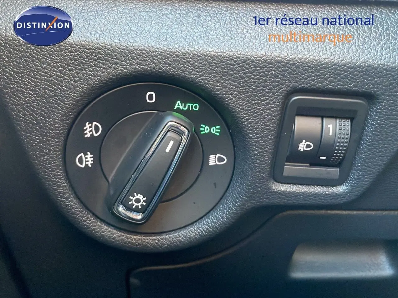 Détail du bouton de commande des phares sur tableau de bord noir du Skoda Kamiq gris graphite 2024.